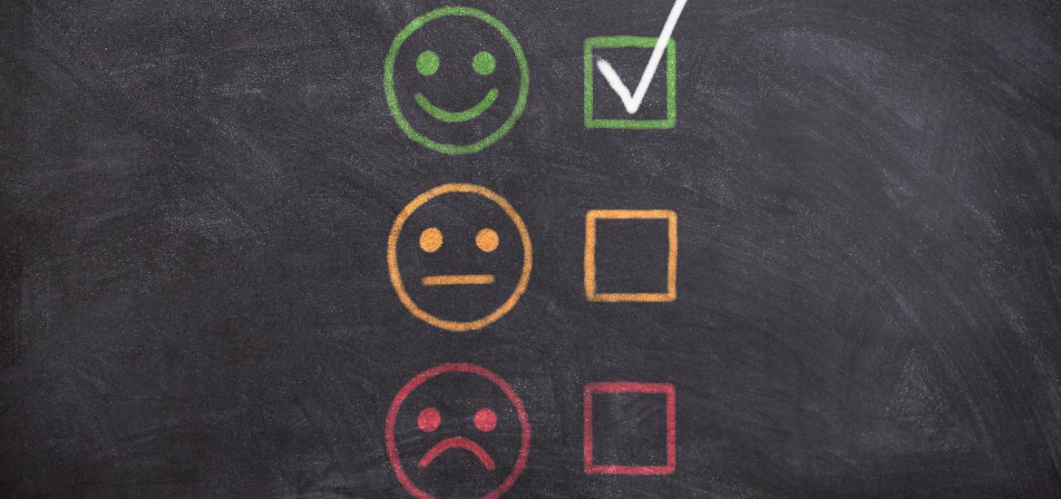 chalkboard with happy, regular, and sad face. Checkmark next to happy face.