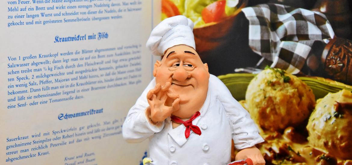 chef standing in front of ingredients and open cookbook