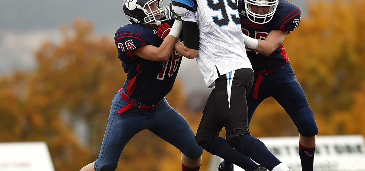 Football (American football) player being blocked by two other players