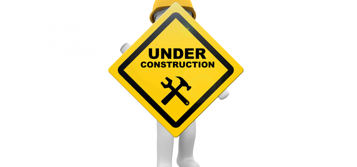 Under construction sign being held by a worker in a hardhat