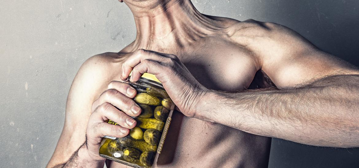 Man struggling to open pickle jar